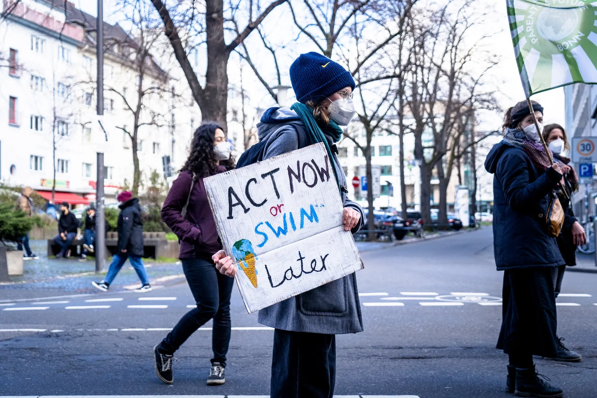 photo of an eco protester with a sign that says 'act now or swim later'