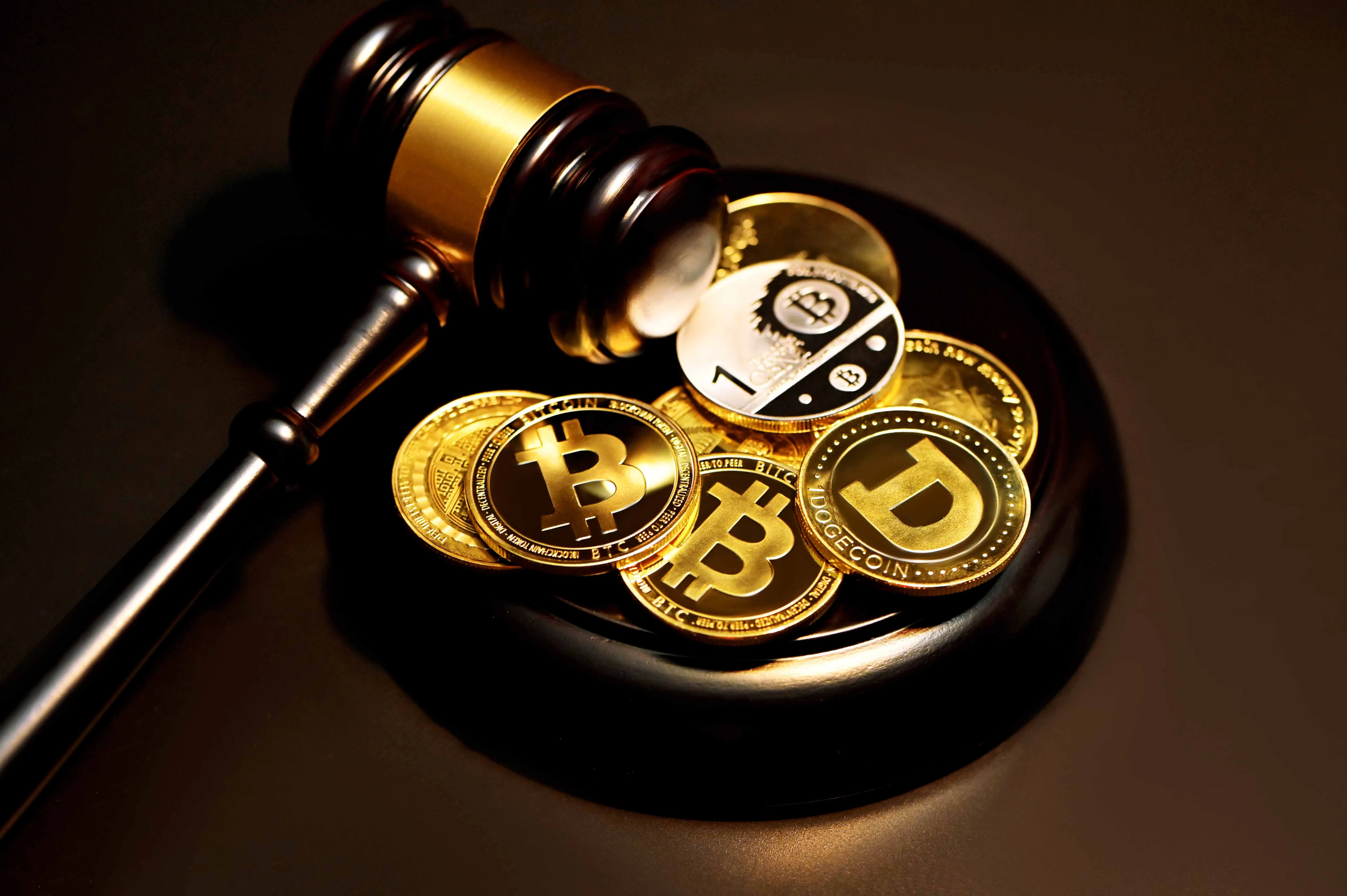 coins with symbols of popular cryptocurrencies next to a judge gavel